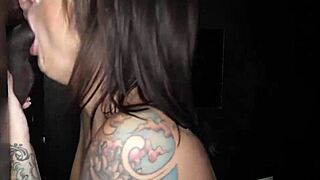 Inked brunette milf with big rack swallows cum at gloryhole spot