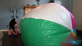 Mega beach ball gets inflated on the beach with black brunette in socks.